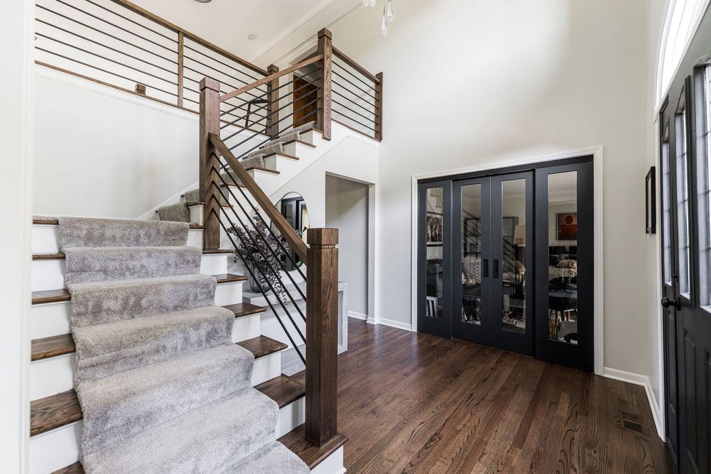 Alyssa Naperville — modern staircase with walnut treads, white painted risers, horizontal iron balusters, and black glass-panel French doors