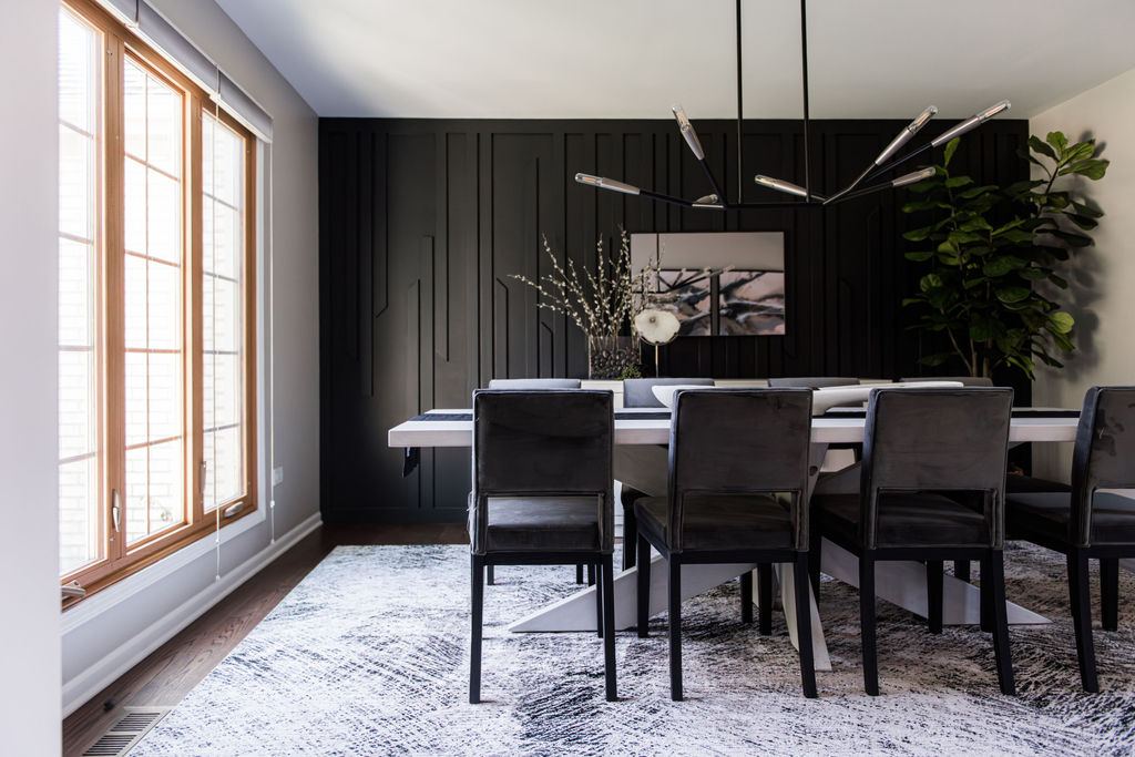 Alyssa Naperville dining room — full-height black paneled accent wall with custom molding detail and modern sputnik chandelier