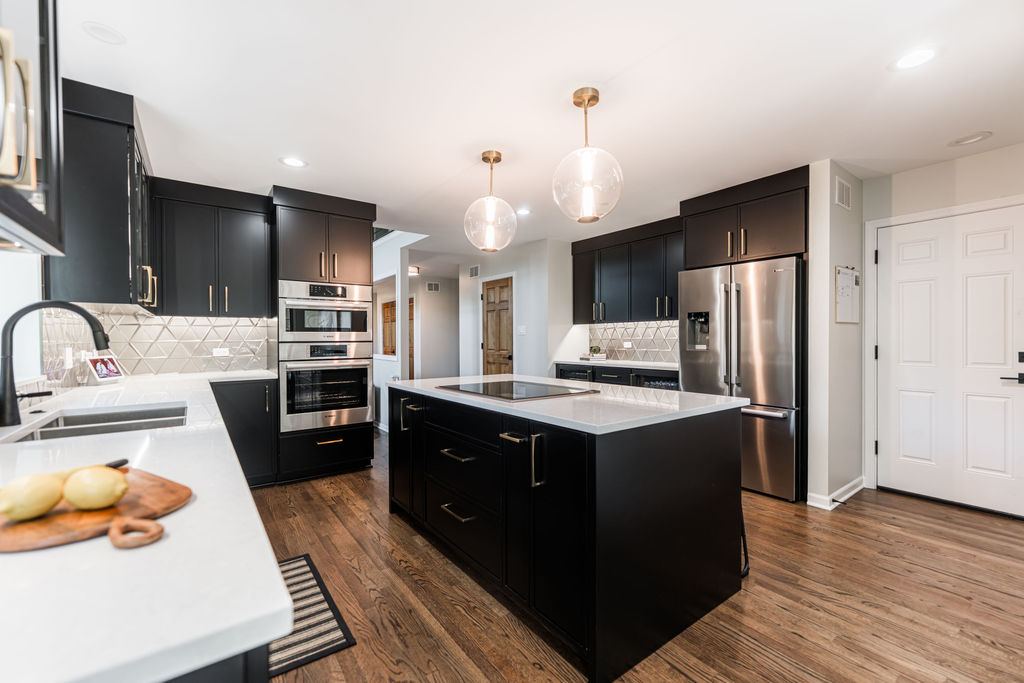 Alyssa Naperville kitchen — detail showing induction cooktop island, geometric metallic backsplash, and matte black faucet