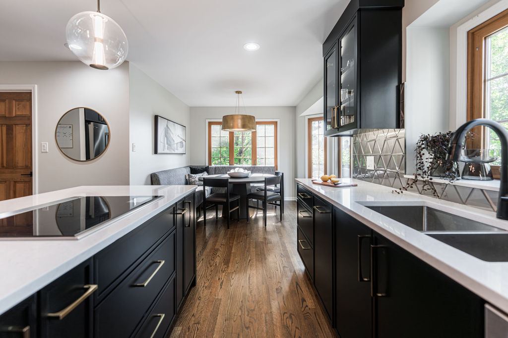 Alyssa Naperville — kitchen island with white quartz waterfall countertop, black base cabinets, and breakfast nook beyond