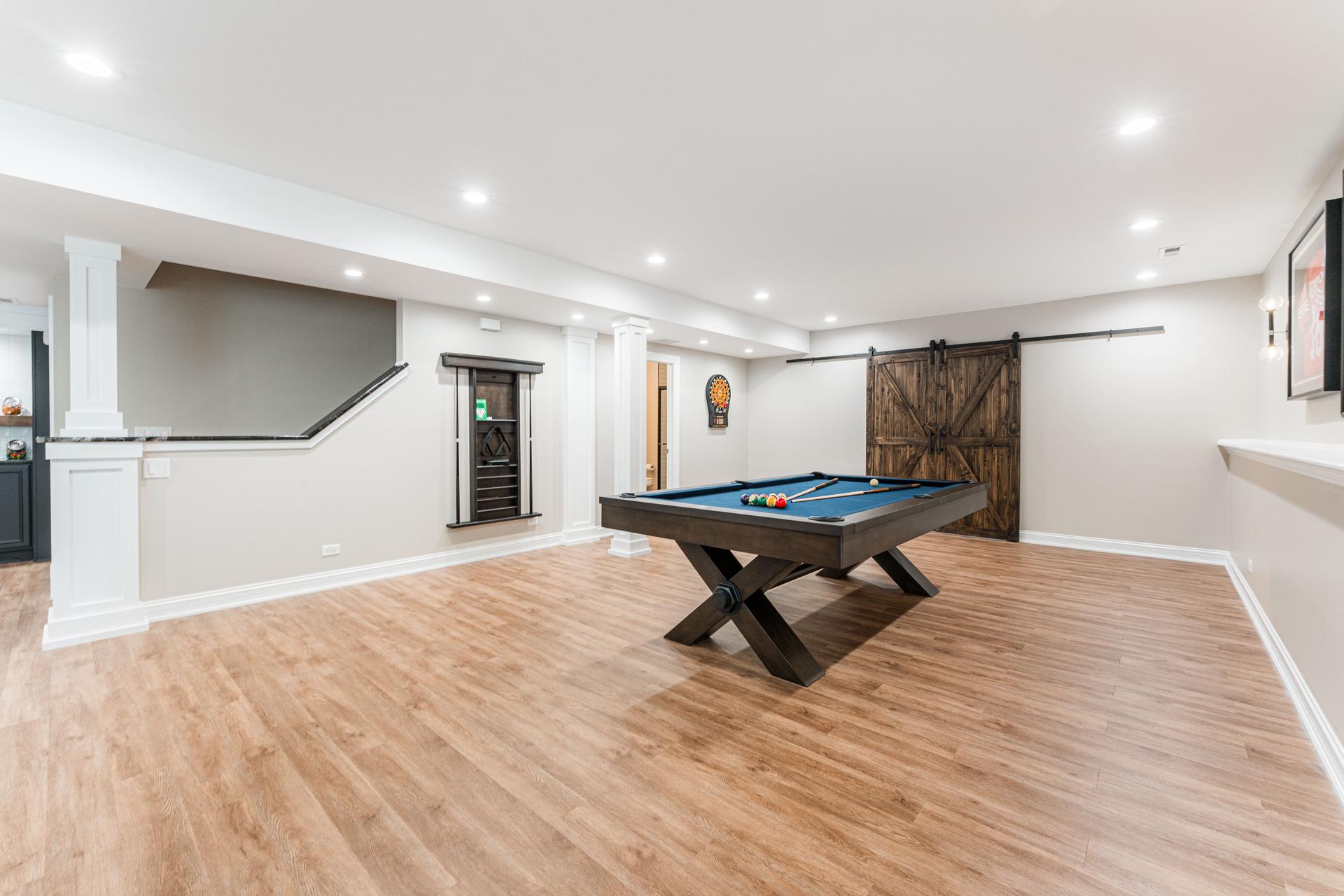 Game room — pool table, barn door entry to full bath, recessed lighting, and staircase — Bealer basement Geneva IL
