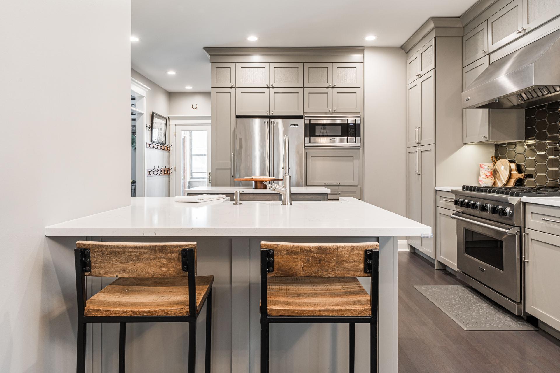 Kitchen peninsula seating with reclaimed wood stools, white quartz, Viking appliance wall beyond — Dillman Plainfield IL
