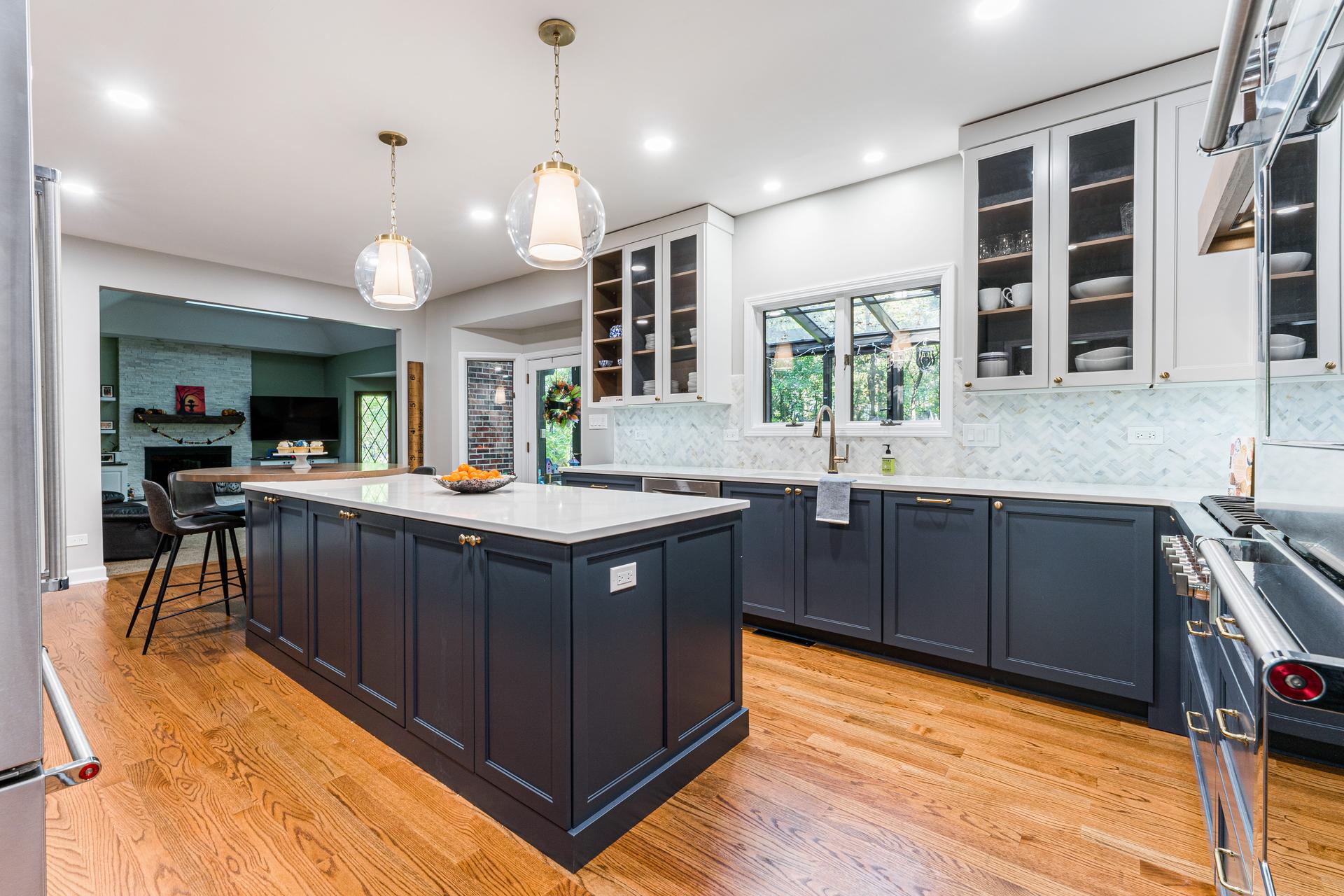 Wide kitchen angle — navy lower cabinets, white uppers with glass doors, oversized island, and Thermador range — Eastcliff kitchen remodel Shorewood IL