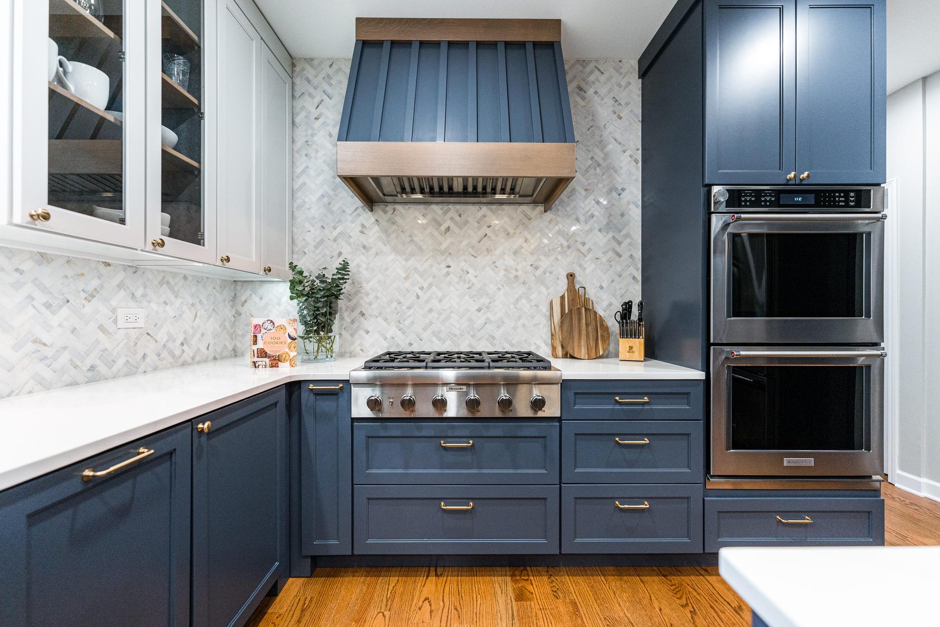 Cooking wall detail — Thermador 6-burner range, custom navy metal hood, marble herringbone backsplash, double wall ovens — Shorewood IL kitchen remodel