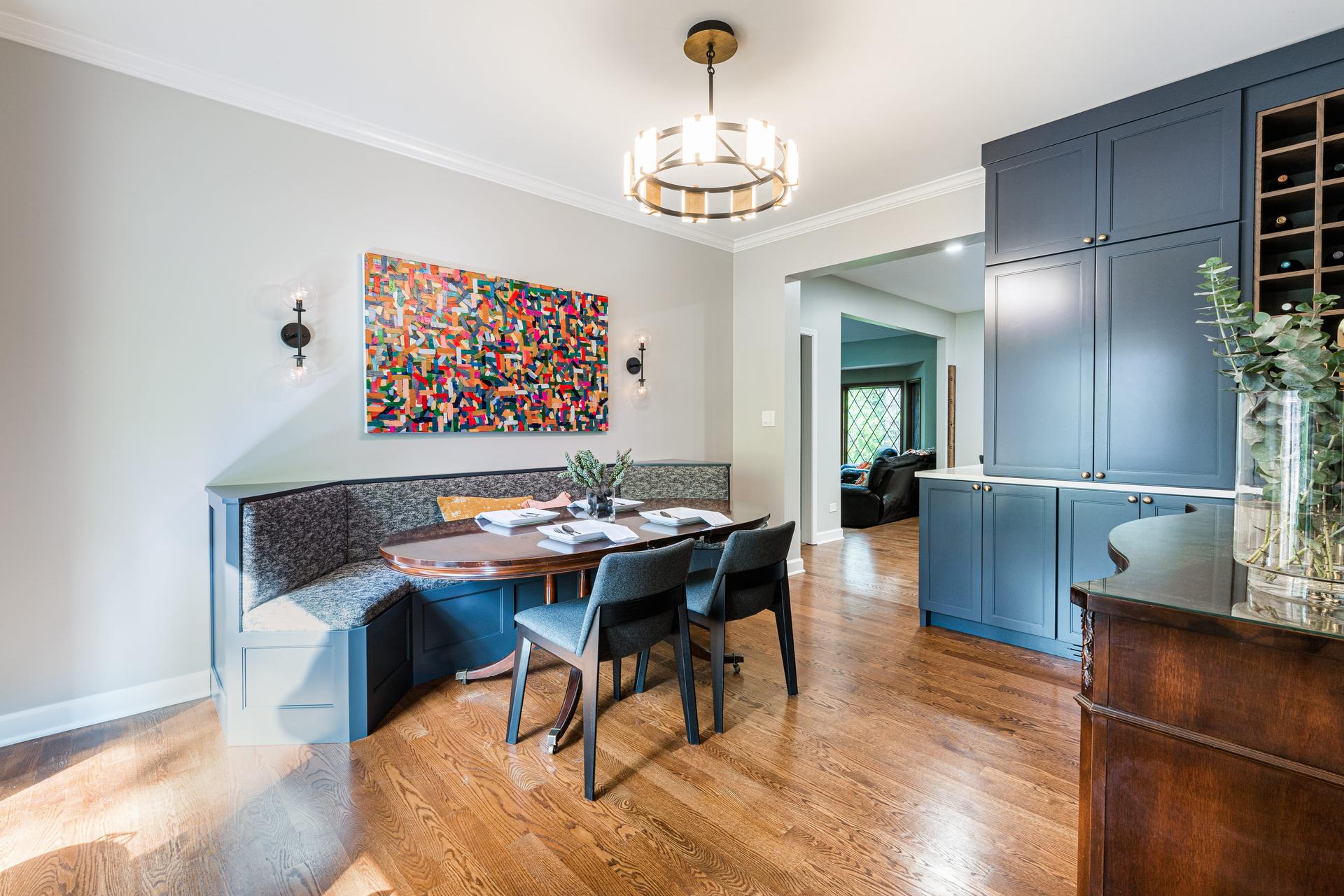 Custom built-in banquette with upholstered bench seating, blue millwork base, and bold abstract art — Eastcliff kitchen remodel Shorewood IL