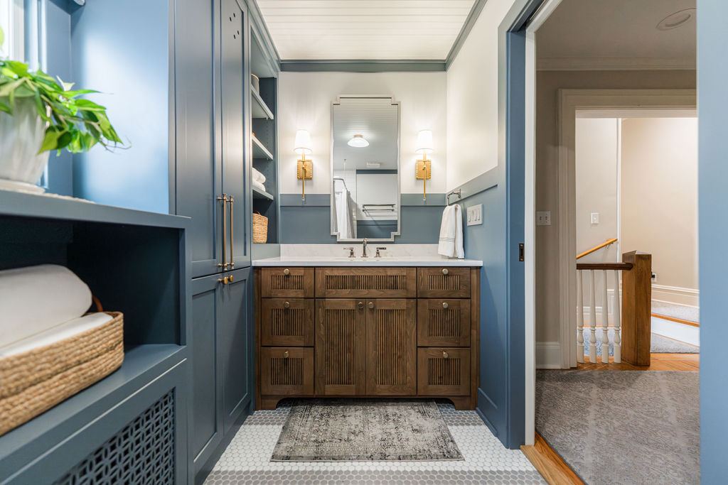 Fulton Geneva boy's bathroom — slate blue cabinetry, walnut fluted vanity, hex tile floor, beadboard ceiling, and brass wall sconces