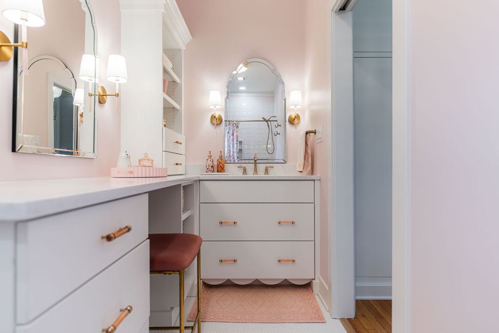 Fulton Geneva girl's bathroom — pink walls, arched vanity mirrors with brass sconces, scalloped cabinetry, and built-in dressing vanity
