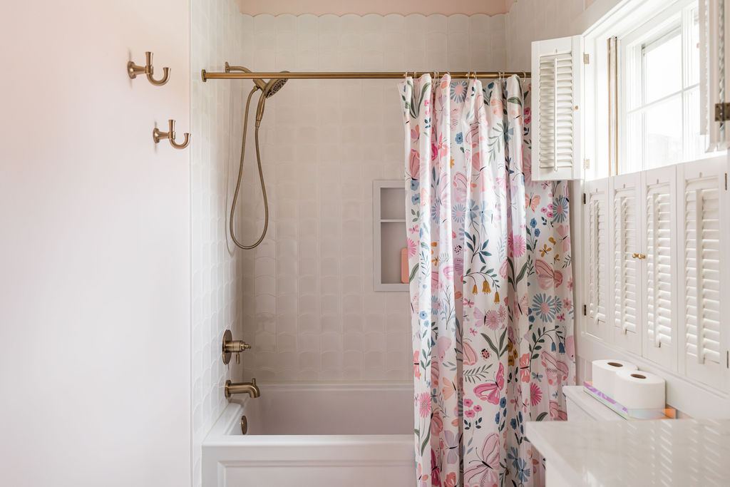 Fulton Geneva girl's bathroom — shower with pink scallop tile border, white subway tile, brass fixtures, and floral curtain