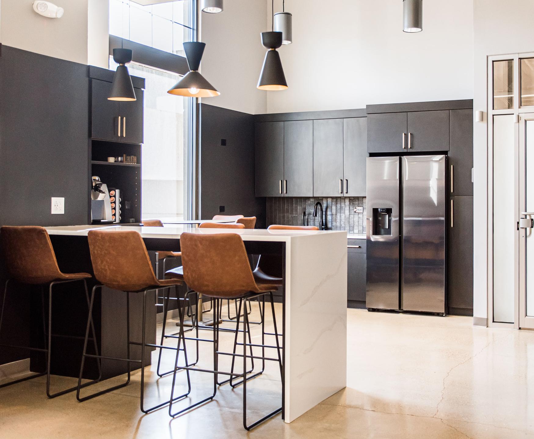 Open kitchen and lounge area with polished concrete floors and industrial pendant lighting — Miller Resource Group, Naperville IL