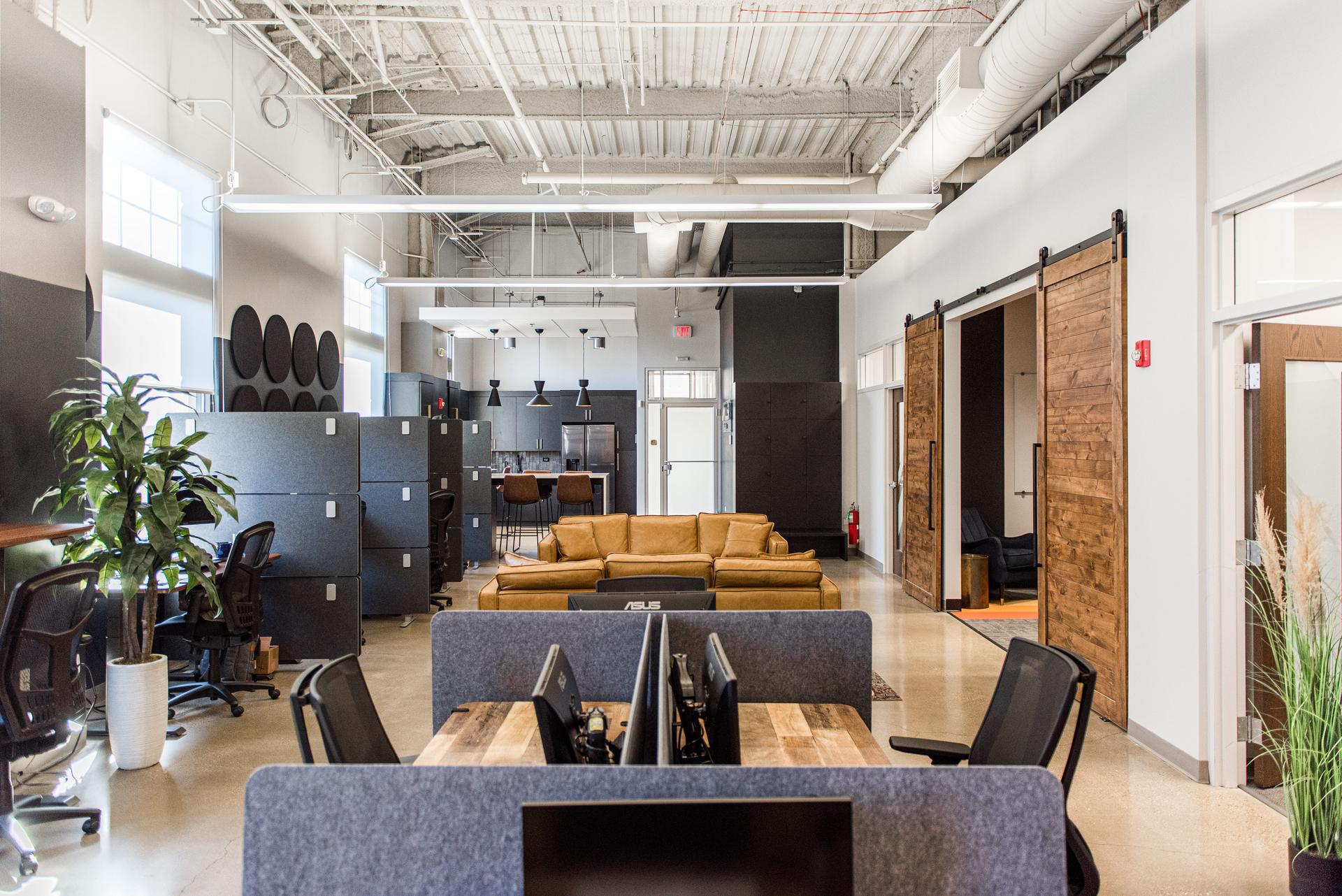 Full open-plan commercial workspace with exposed ductwork, acoustic panels, and custom millwork barn doors — Naperville commercial build