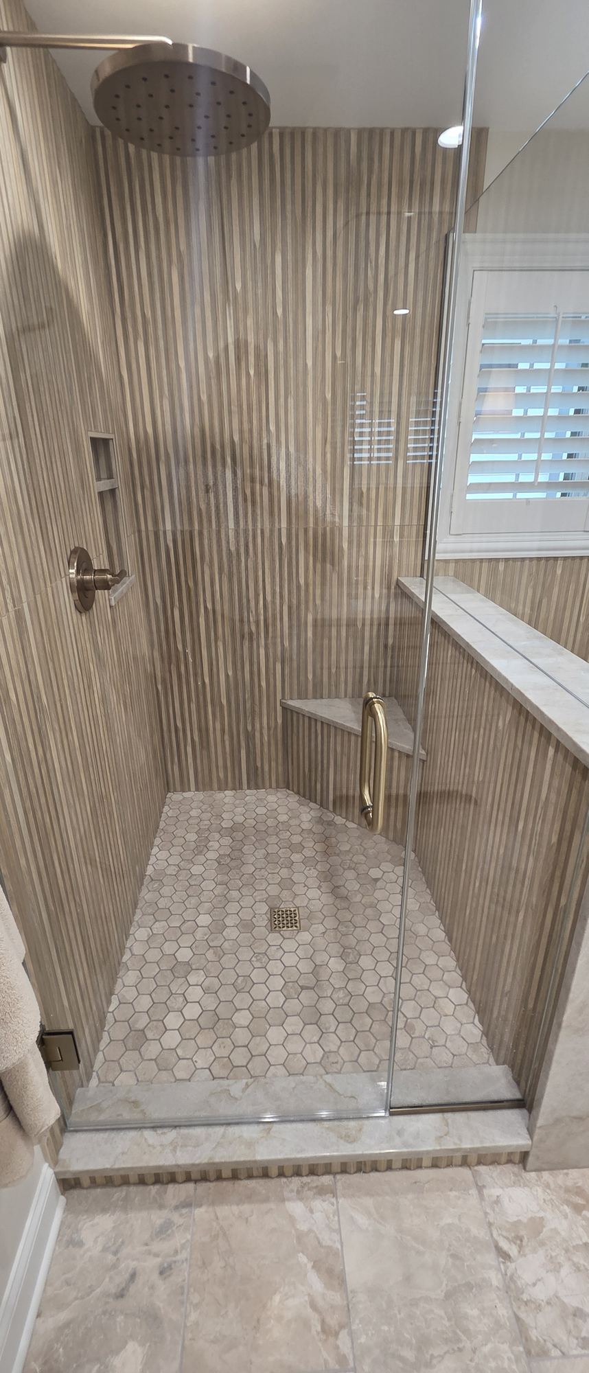 Park Ridge primary bathroom — walk-in shower with rain head, built-in niche, corner marble bench and hexagon marble mosaic floor