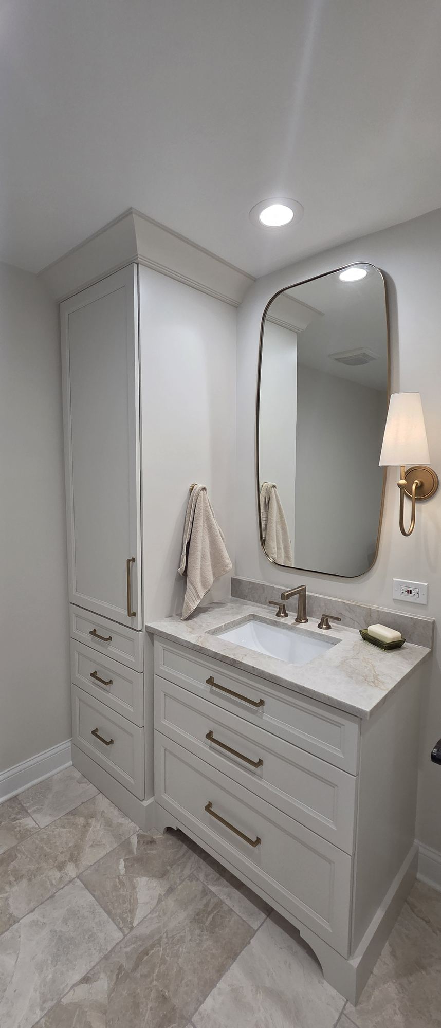 Park Ridge primary bathroom — warm white vanity with marble top, brushed brass hardware and tall linen tower